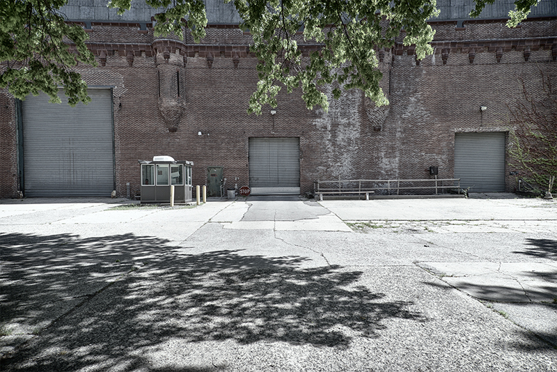 Facade of armory, deep shadows cast by trees.