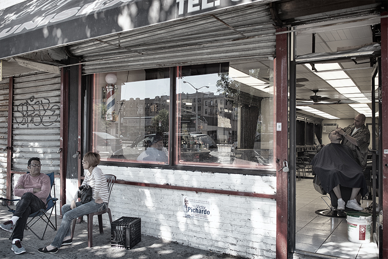 Barber shop with patrons sitting outside.