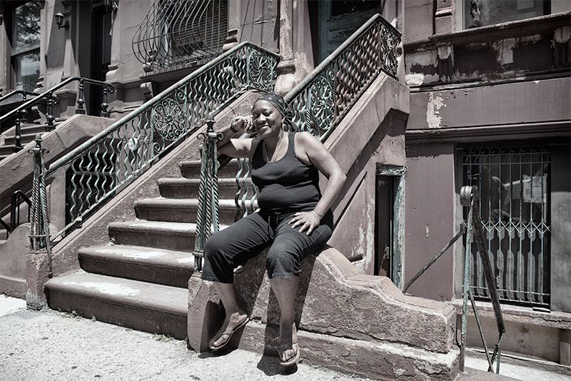 Woman sitting in front of brownstone on 120th.