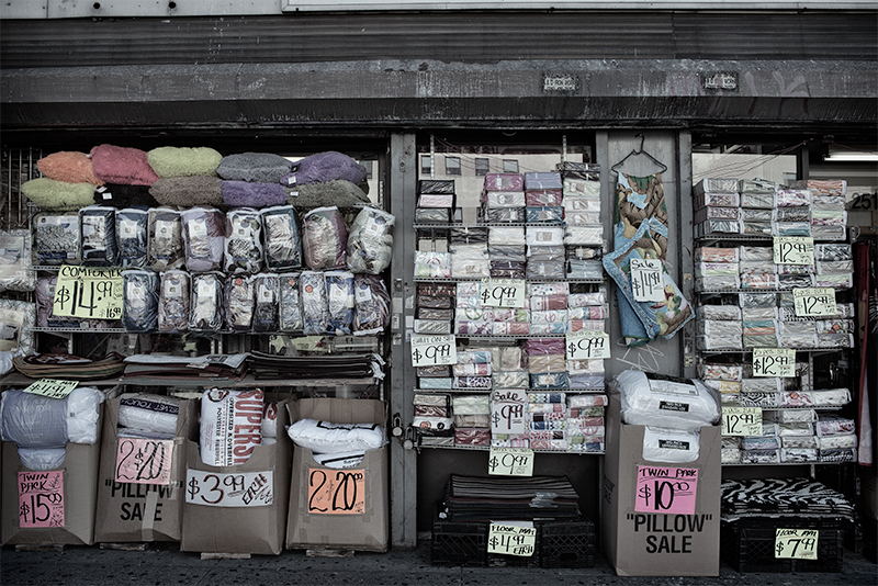 Facade of store packed with linens, advertising sales.