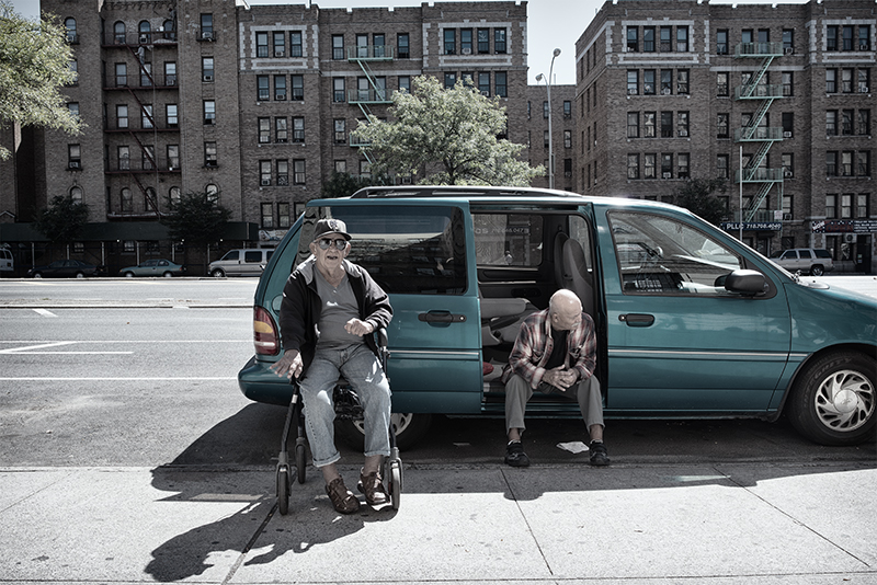 Two men, one in wheelchair, outside a green van on the Concourse.