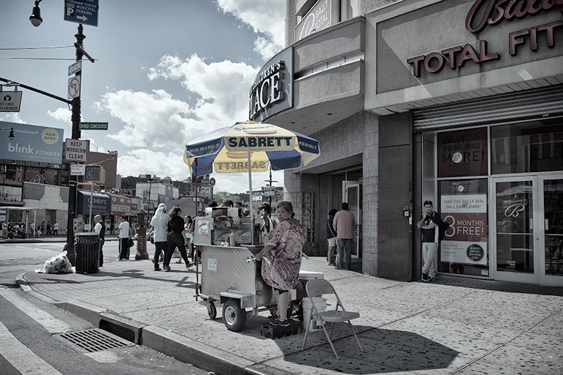 A lady hot dog vendor looks over her shoulder toward the photographer.