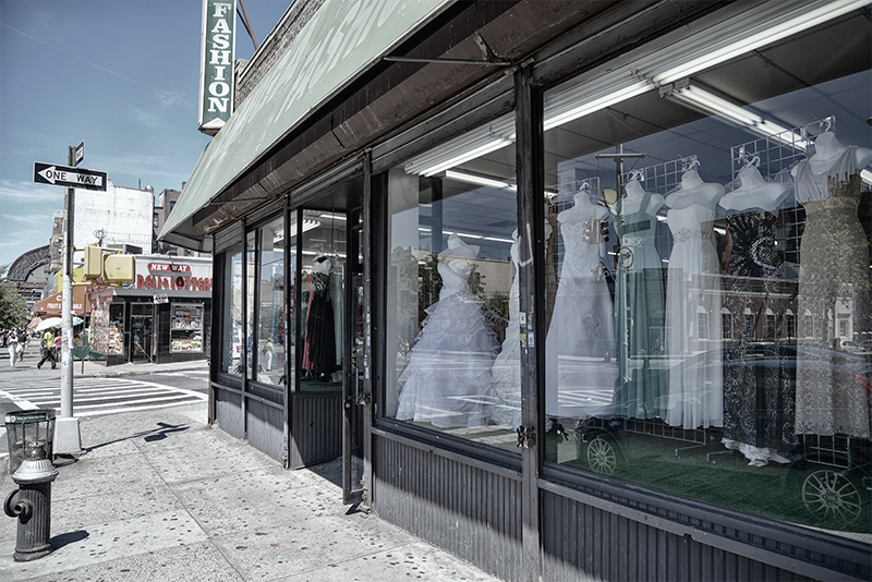 Evening gowns on mannequins in storefront display.