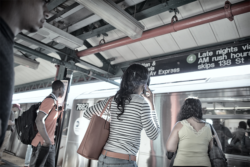 Young woman on phone, waiting for subway