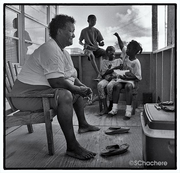 Woman and three children on porch of house.