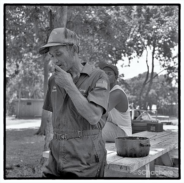 Man smoking cigarette in front of picnic table