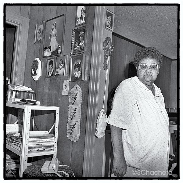 Woman standing by paneled wall of photos.