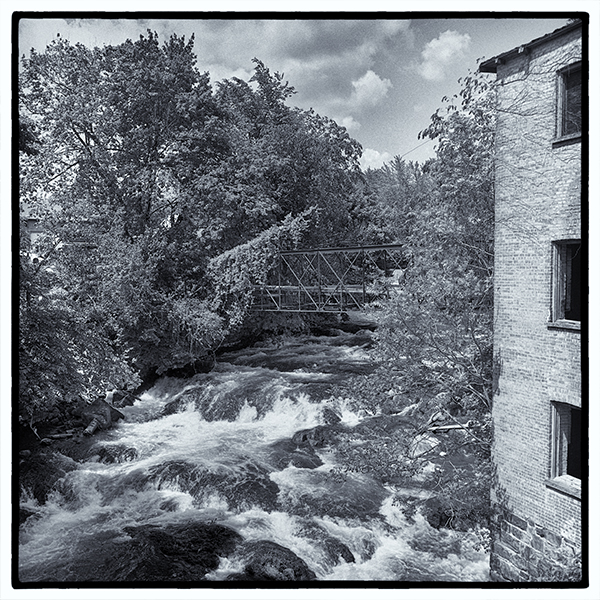 Waterfall between trees and brick facade