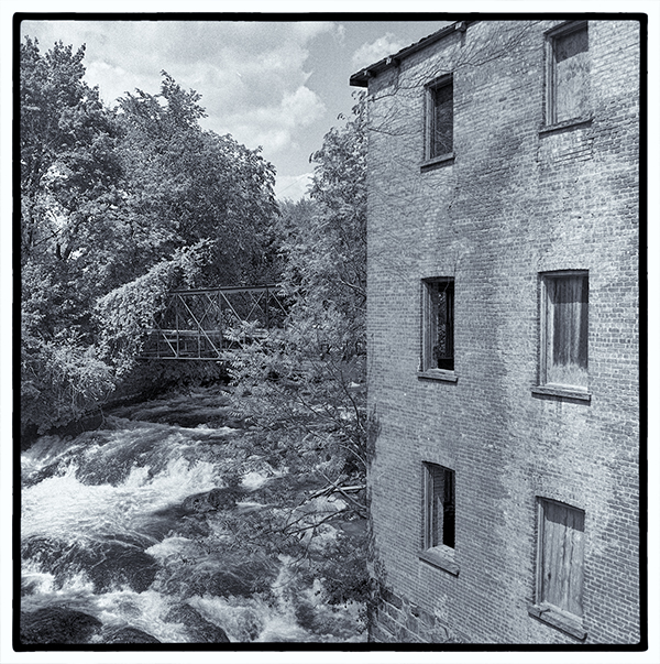 Waterfall between trees and brick facade